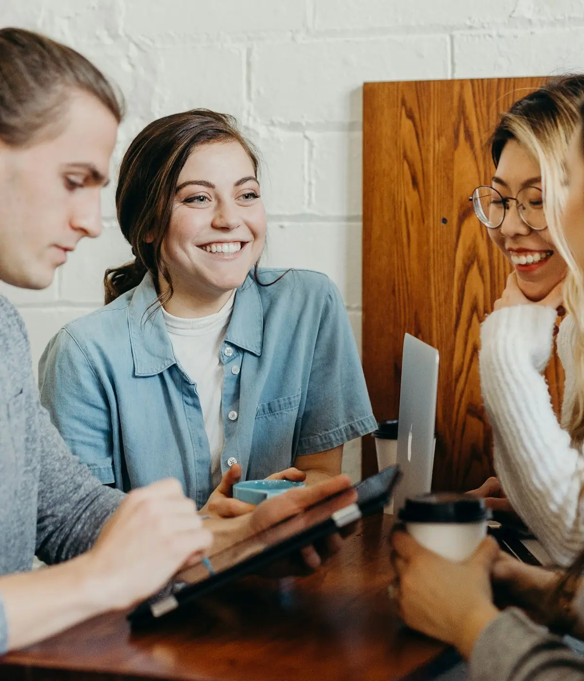 Friends comparing notes around a laptop at a cafe table
