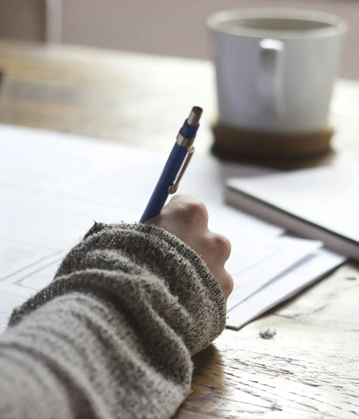 Student taking handwritten notes next to a coffee cup